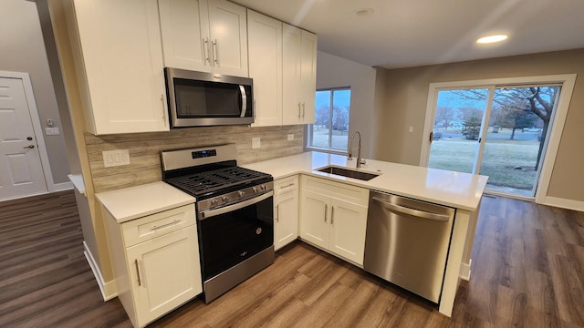 kitchen featuring white cabinets, sink, stainless steel appliances, and kitchen peninsula