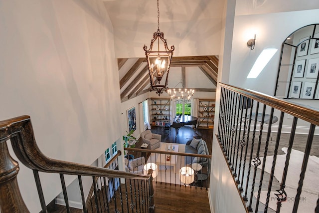 stairs featuring wood finished floors, baseboards, high vaulted ceiling, an inviting chandelier, and beam ceiling