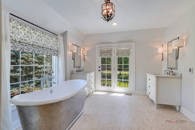 bathroom featuring a soaking tub, a sink, baseboards, and two vanities