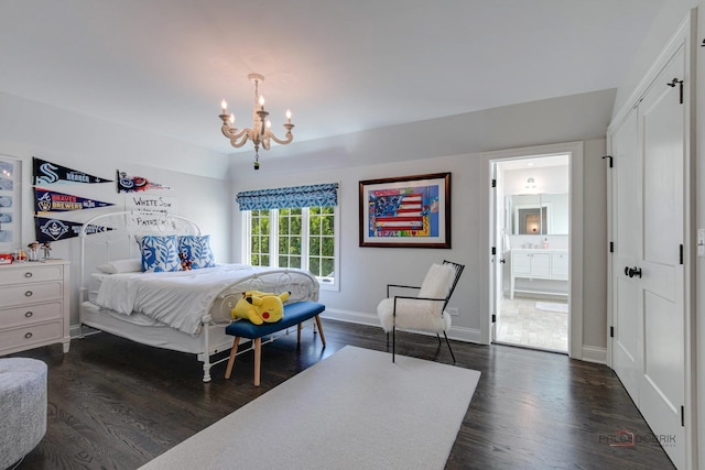 bedroom with dark wood-type flooring, a notable chandelier, baseboards, and ensuite bathroom