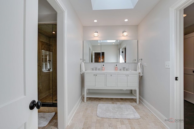 full bathroom with baseboards, double vanity, a skylight, a sink, and a shower stall