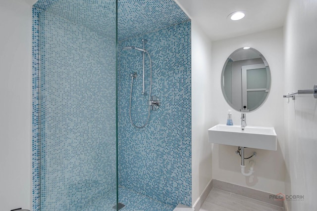 bathroom with a sink, baseboards, and a tile shower