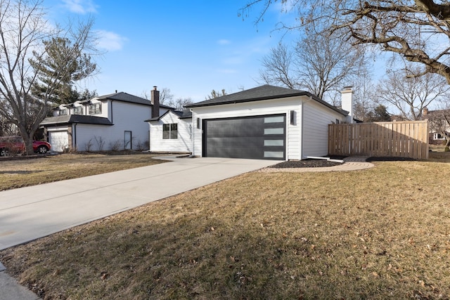 view of front of property featuring a front lawn, driveway, fence, a garage, and a chimney