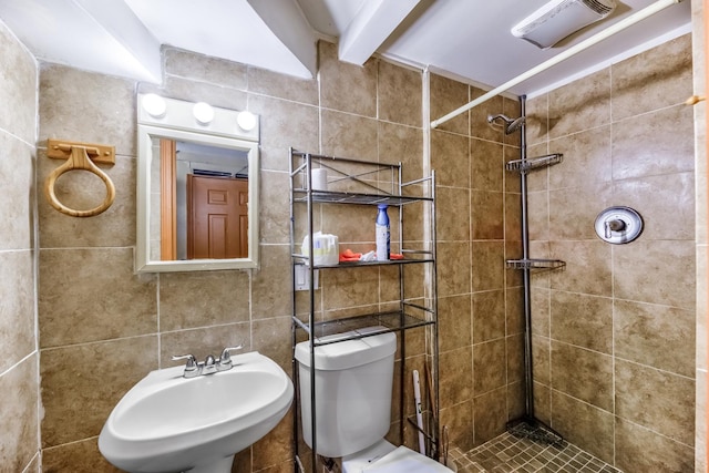 bathroom with tile walls, sink, tiled shower, and toilet