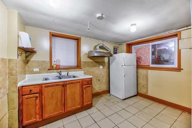 kitchen featuring white refrigerator, sink, tile walls, and light tile patterned floors