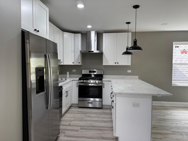 kitchen featuring appliances with stainless steel finishes, wall chimney range hood, light wood-type flooring, and a peninsula