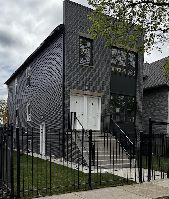 view of front of home featuring a front yard, brick siding, and a fenced front yard