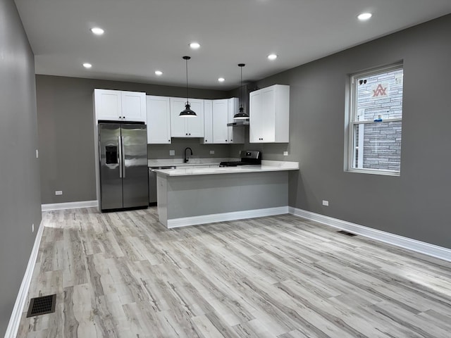 kitchen with light wood finished floors, visible vents, a peninsula, light countertops, and appliances with stainless steel finishes