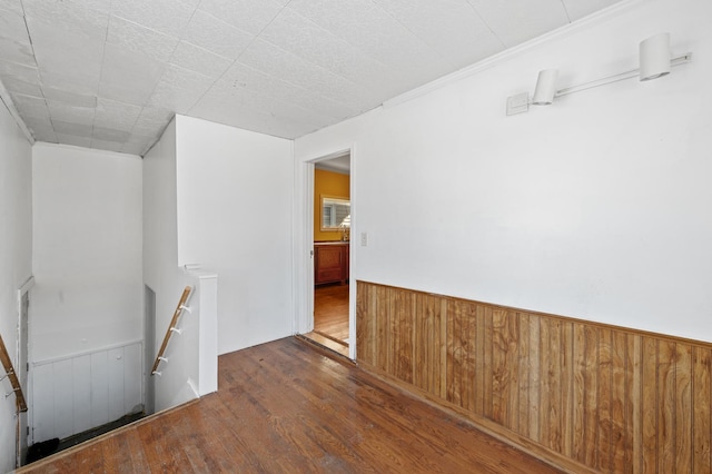 spare room with dark wood-style flooring, wainscoting, and wooden walls