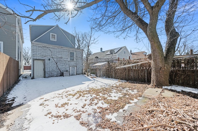 snow covered rear of property featuring fence