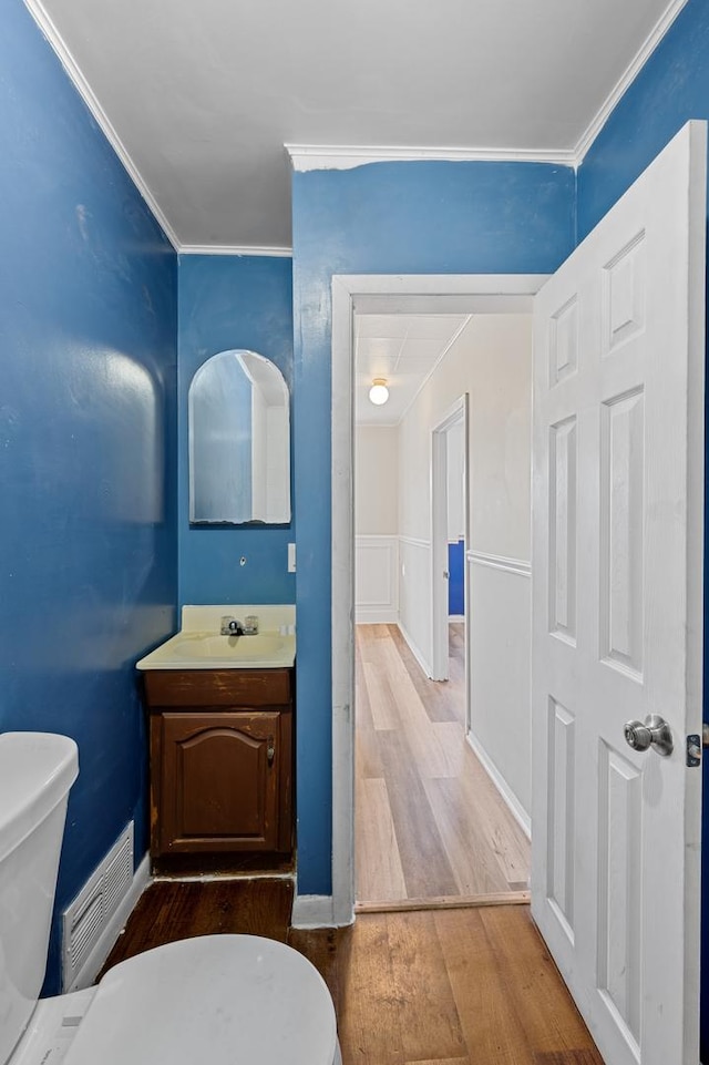 bathroom with ornamental molding, vanity, toilet, and wood finished floors