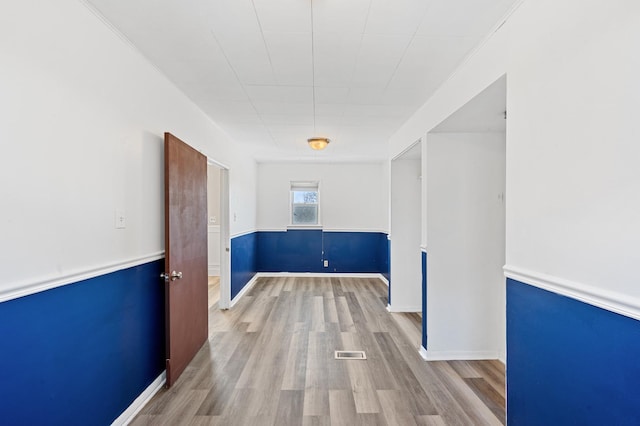 empty room with light wood-type flooring, baseboards, and visible vents