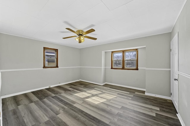 empty room with wood finished floors, a ceiling fan, and baseboards