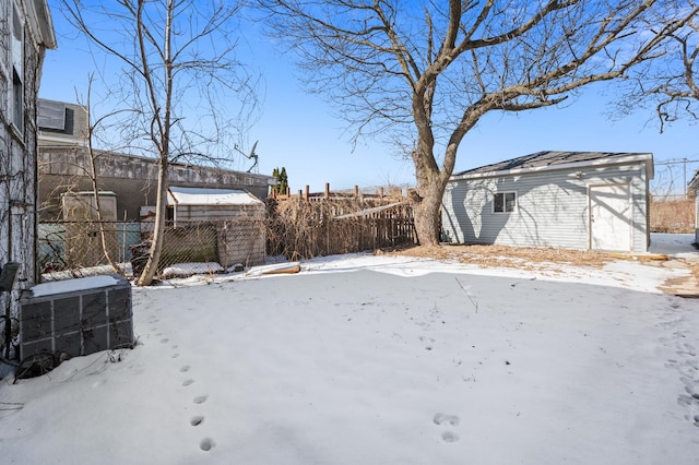 yard covered in snow featuring central AC, an outdoor structure, and fence