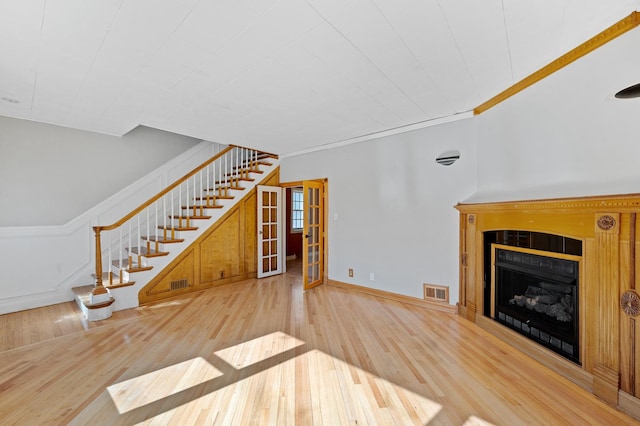 unfurnished living room featuring stairs, visible vents, a fireplace, and wood finished floors