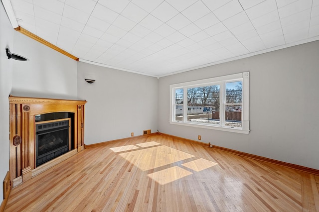 unfurnished living room with ornamental molding, a fireplace, light wood finished floors, and baseboards