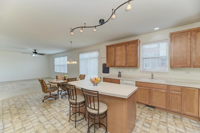 kitchen with hanging light fixtures, a healthy amount of sunlight, sink, and a kitchen island