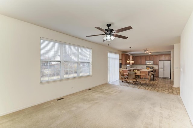 unfurnished living room featuring ceiling fan and light carpet