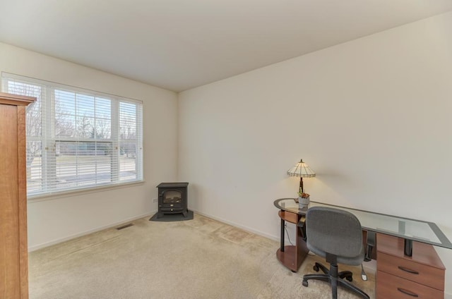 carpeted office space featuring a wood stove