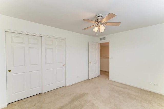 unfurnished bedroom featuring ceiling fan, a closet, and light colored carpet