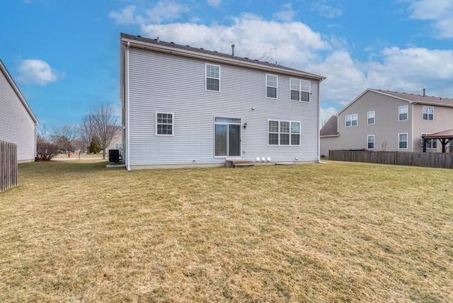 rear view of property with central AC unit and a yard