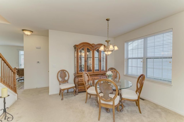 dining space with light carpet and a chandelier