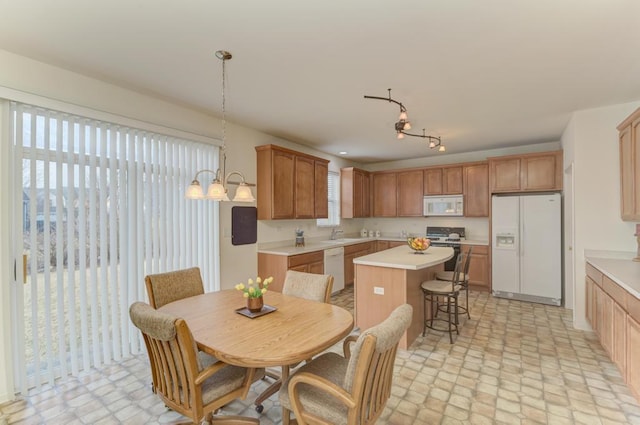 kitchen with a center island, a notable chandelier, sink, white appliances, and pendant lighting