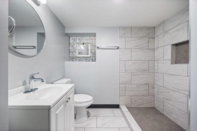 bathroom featuring vanity, tiled shower, and toilet