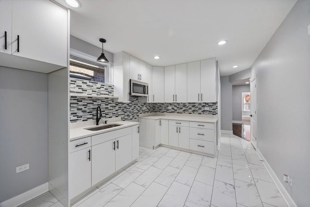 kitchen featuring white cabinetry, pendant lighting, sink, and tasteful backsplash