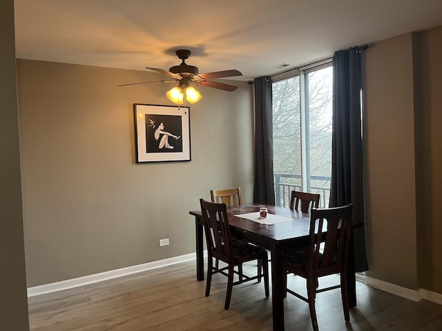 dining room featuring ceiling fan, dark wood-type flooring, a wealth of natural light, and a wall of windows