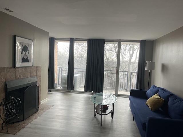 living room featuring light hardwood / wood-style flooring, a tile fireplace, and expansive windows