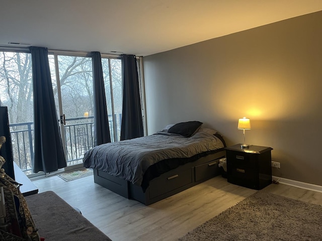 bedroom with light hardwood / wood-style floors, expansive windows, and access to exterior