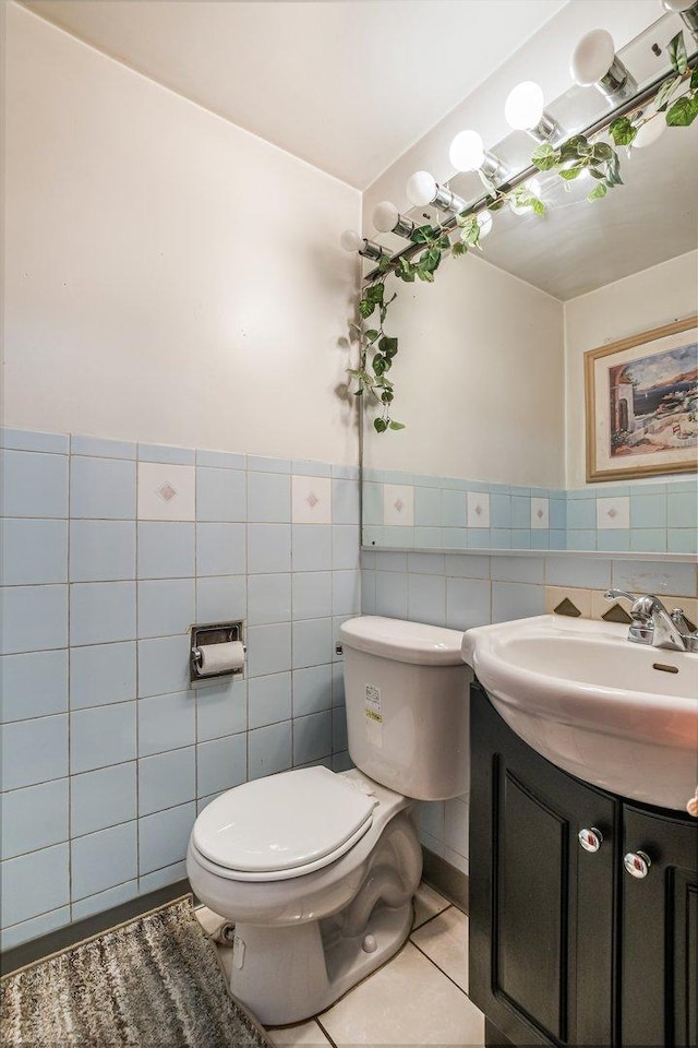 bathroom with vanity, tile patterned flooring, wainscoting, tile walls, and toilet