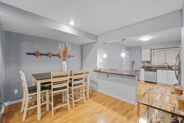 dining space with light wood-type flooring and sink