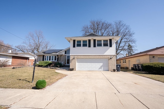 split level home with brick siding, solar panels, an attached garage, a front yard, and driveway