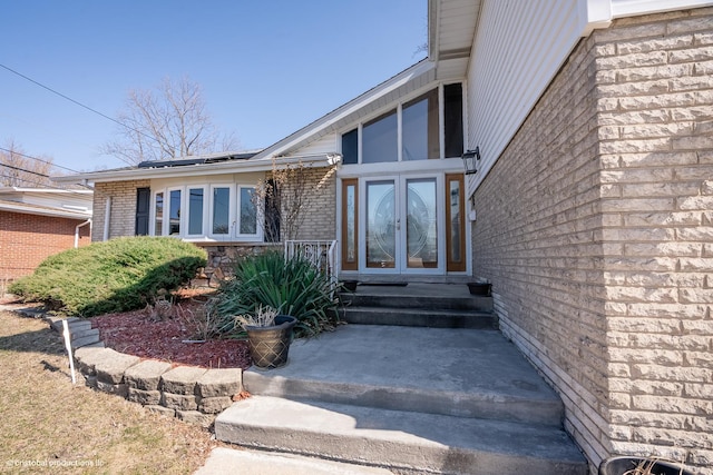 doorway to property featuring brick siding, solar panels, and french doors