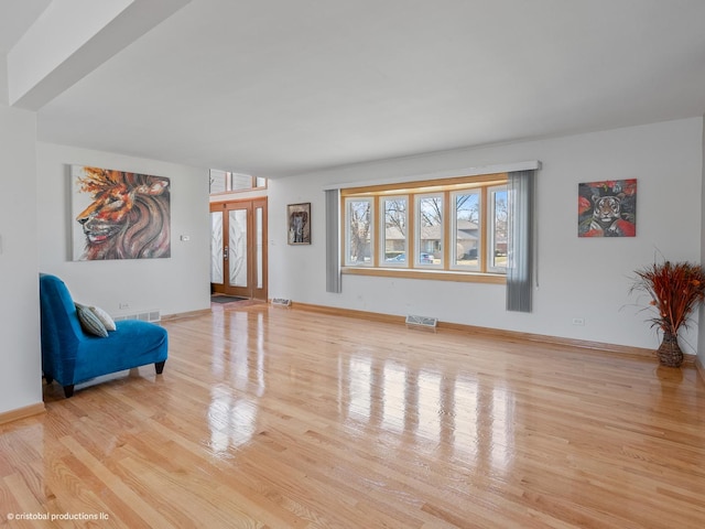 living area with wood finished floors, visible vents, and baseboards