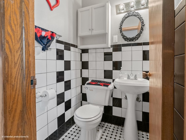 bathroom with tile walls, toilet, and a wainscoted wall