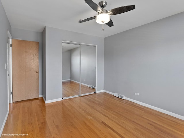 unfurnished bedroom featuring light wood-type flooring, visible vents, baseboards, and a closet