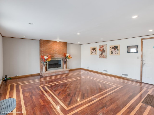 unfurnished living room with visible vents, a brick fireplace, baseboards, and wood finished floors