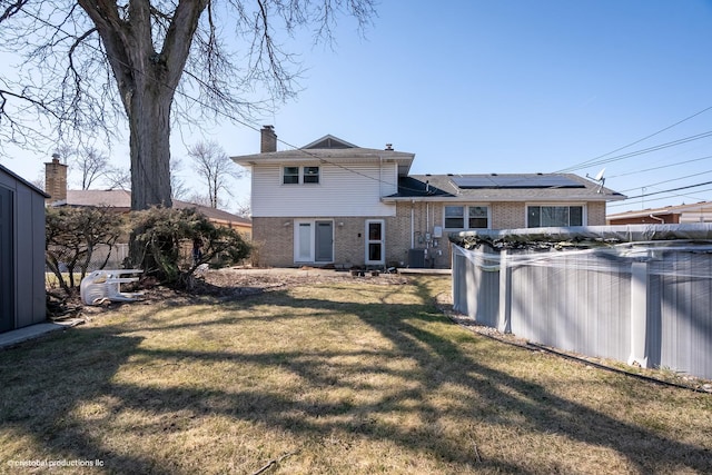 rear view of property featuring a yard, a fenced in pool, brick siding, and central AC