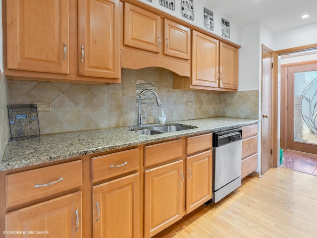 kitchen with light stone counters, a sink, decorative backsplash, light wood-style floors, and stainless steel dishwasher