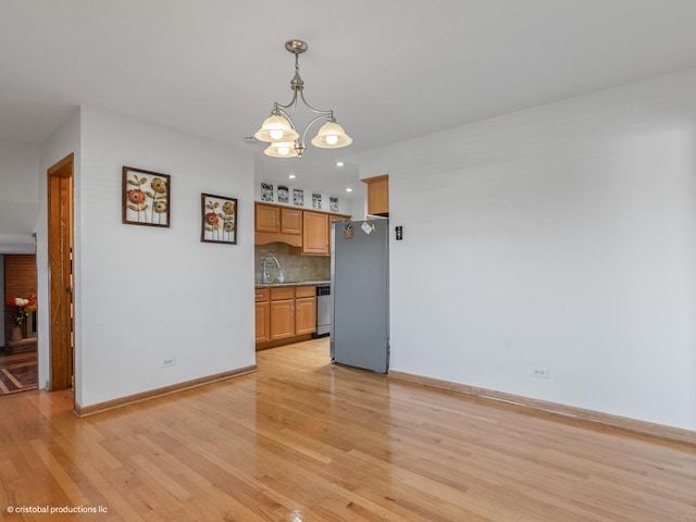 interior space with a notable chandelier, light wood-type flooring, baseboards, and a sink