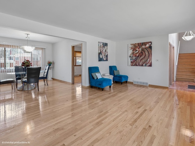 living area with stairway, baseboards, visible vents, and light wood finished floors