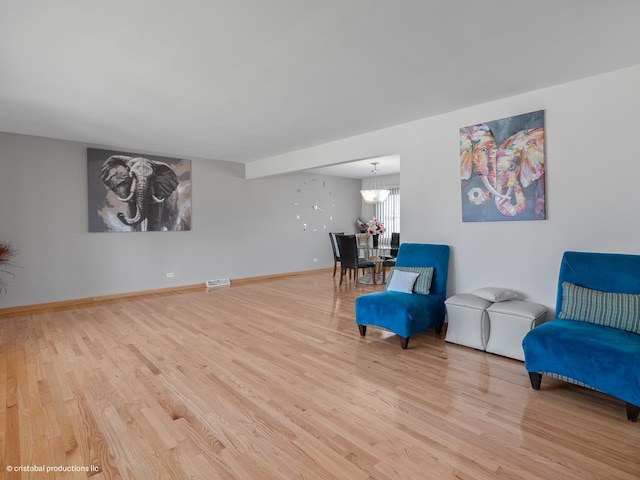 sitting room with a notable chandelier, visible vents, baseboards, and wood finished floors