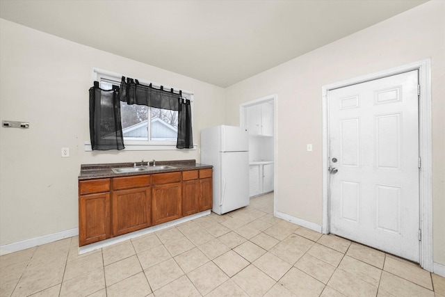 kitchen with white fridge, sink, and light tile patterned floors