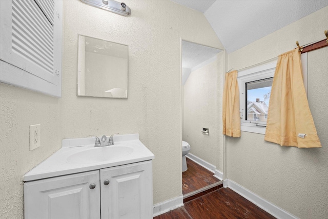 bathroom with lofted ceiling, wood-type flooring, vanity, and toilet