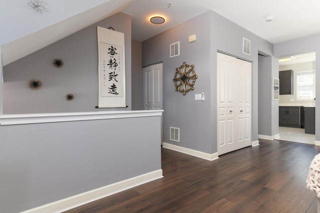 hallway featuring lofted ceiling and dark wood-type flooring