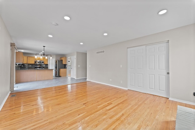 unfurnished living room featuring light wood-style flooring, visible vents, and recessed lighting