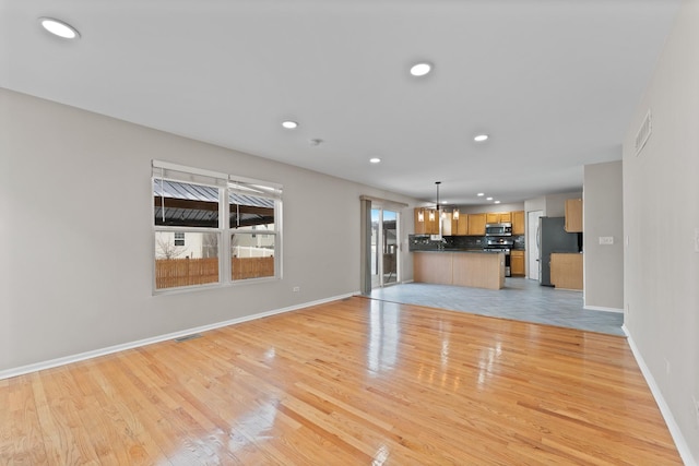 unfurnished living room with light wood-style flooring, visible vents, baseboards, and recessed lighting